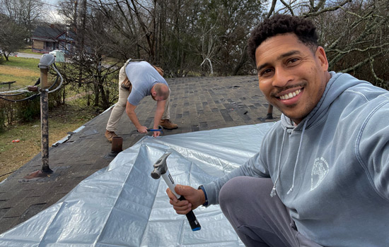 Nes and William putting a tarp on a roof